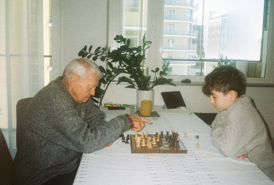 Senior Man and a Boy Playing Chess At Home