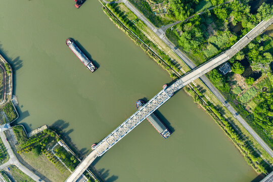 highway bridge over river with cargo barges passing below