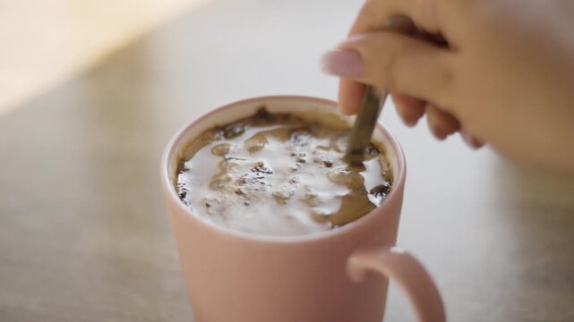 Close-up of adding sugar and stirring cold iced coffee in a glass