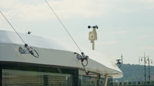 An anemometer spins on the roof of a vessel to measure wind speed. Meteorological equipment monitors weather data during maritime navigation. Nautical technology tracks atmosphere conditions.