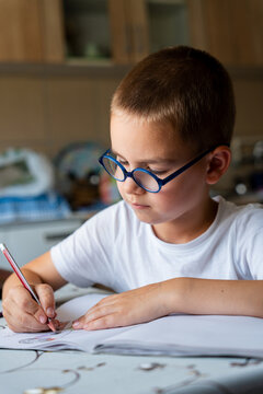 Young Boy Drawing in Sketchbook at Home