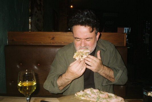 Man Enjoys Pizza at at Italian Restaurant 