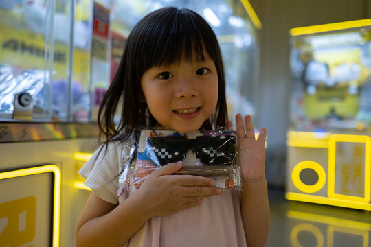 Child in Arcade Holding Prize From Claw Machine