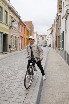 Smiling Mid Adult Man Riding Bicycle on Bruges Cobblestone Street