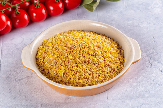 Bowl of golden bulgur wheat with fresh cherry tomatoes on vine