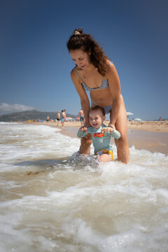Mother and son enjoying beach vacation playing in ocean waves