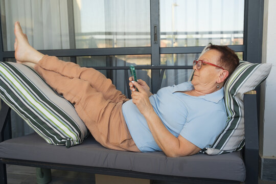 Senior Woman Relaxing on a Lounge Chair While Using Her Phone