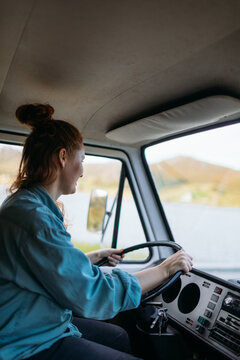 Woman smiling driving vintage campervan enjoying road trip
