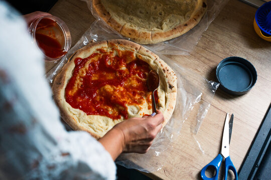 Spreading Tomato Sauce on Homemade Pizza Dough
