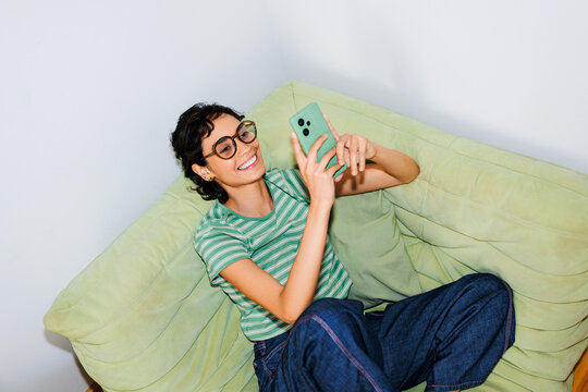Woman relaxing on couch using smartphone for social media ugc