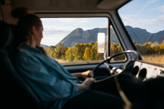 Woman driving camper van feeling freedom on road trip