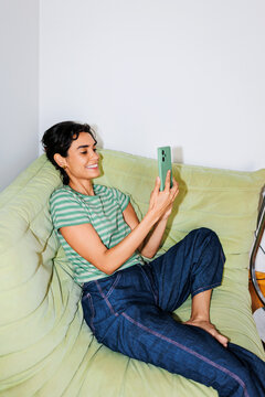 Woman smiling enjoying video call on smartphone at home ugc