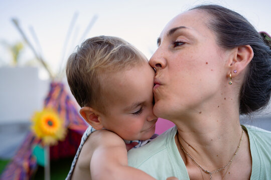 Mother kissing forehead of her son showing love
