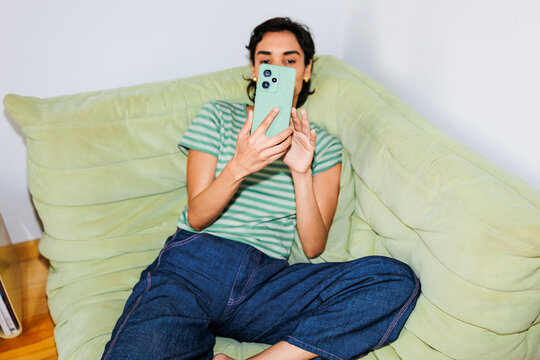 Woman relaxing on beanbag using smartphone recording video ugc