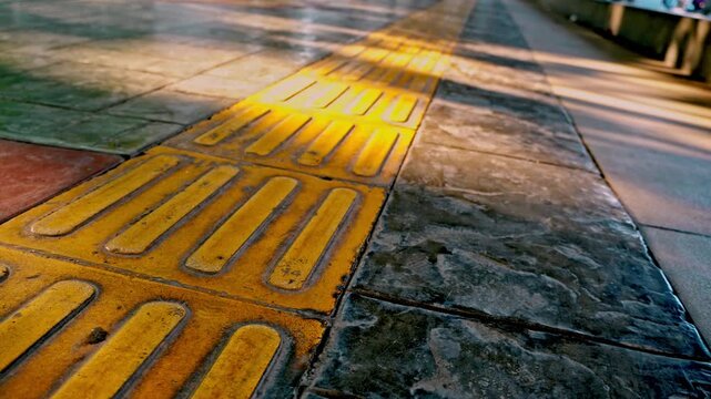 Smooth forward tracking camera movement over tactile paving tiles and yellow guide blocks on a public pedestrian walkway in the historic old town of Gresik, Indonesia.