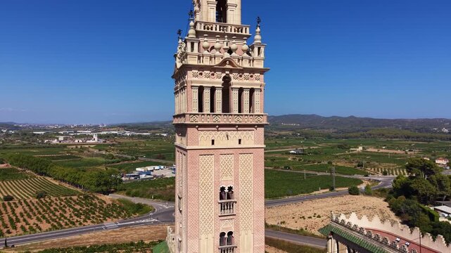 Close-up aerial view of an ornate Neo-Mudejar minaret-style tower in Catalonia, Spain, featuring intricate brickwork, arabesque patterns, and decorative pinnacles