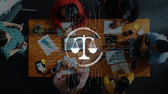 Aerial view of a diverse professional team collaborating on data analytics in a modern office, featuring a legal scales icon overlay symbolizing justice and balance. Raster