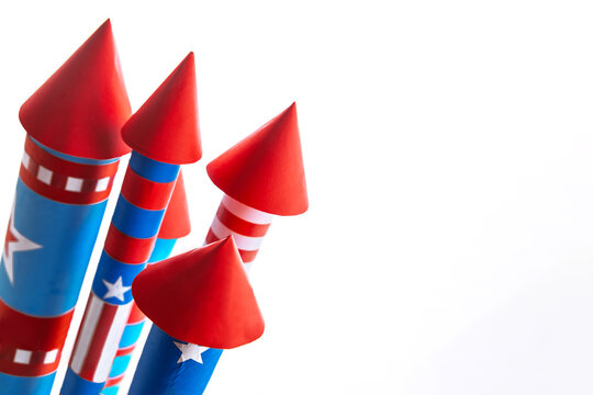 Fourth of July USA Independence Day festive celebration concept with copy space. Handmade craft paper rockets decorated with stars and stripes, isolated on white background.