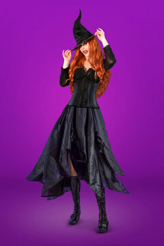 Witch on Halloween. Female wizard fairy character for All Saints' Day. Fantasy gothic red-haired Vampire girl in black dress. Enchantress dressed in carnival costume