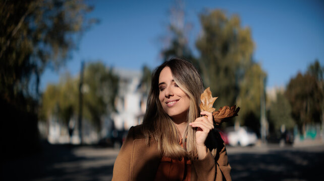 Stressed Young Woman Searching Her Handbag For Lost Item On Park Bench. Anxious female sitting on wooden bench outdoors in autumn trying to find missing objects inside purse