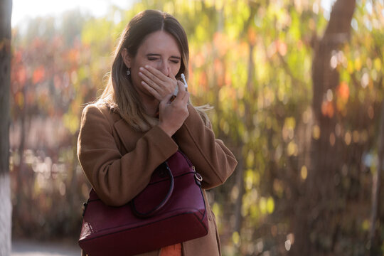 Sick Young Woman Outdoors Holding Medication Bottle For Sore Throat Relief. Unwell female patient covering her mouth preparing throat spray to treat acute pharyngitis 