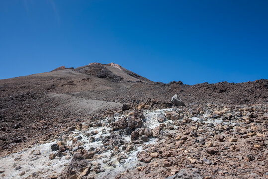 View of Mount Teide&rsquo;s upper cone, showing the steep volcanic slope, loose rock terrain and rugged lava formations under a clear, intense blue sky