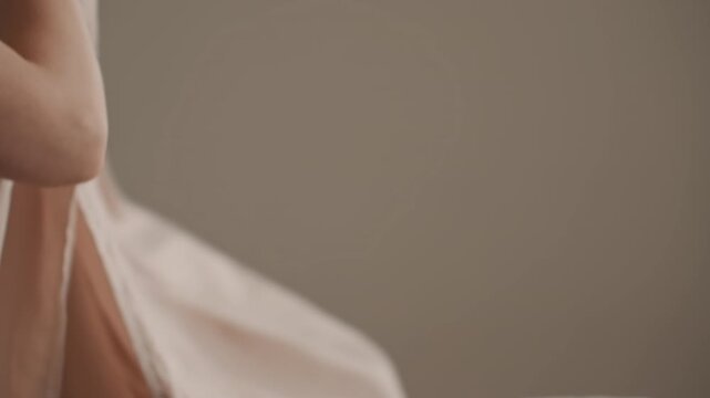 White woman wrapping pale sheet closeup, bob haircut, soft beige background, gentle hands smoothing linen, slow motion gestures, close texture study, tender minimal mood, tasteful domestic solitude