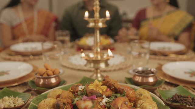 Indian festive dinner table with lit brass oil lamp and food