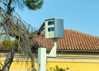 Roadside traffic enforcement camera by tiled roof in sunny Agia Paraskevi Greece