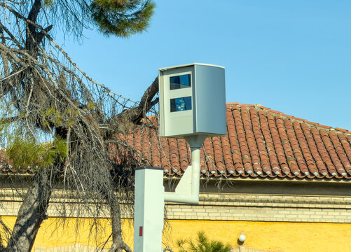 Roadside traffic enforcement camera by tiled roof in sunny Agia Paraskevi Greece