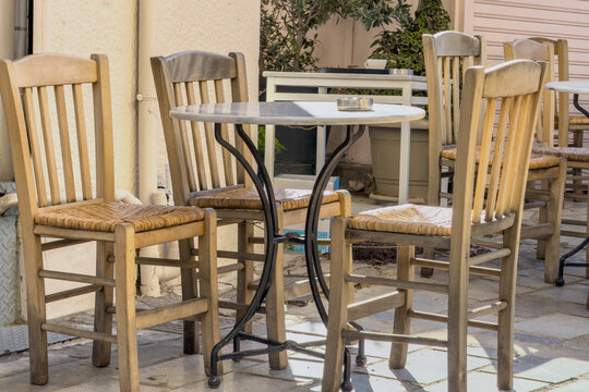 Outdoor cafe empty wooden chairs around a marble table in Monastiraki, Athens, Greece