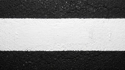 Fototapeta premium Bold white painted line on rough black asphalt texture, creating a striking contrast and clear road marking stripe