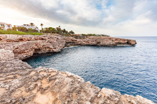 Weathered cliffs above calm water in Cala d'Or, Mallorca, Spain.