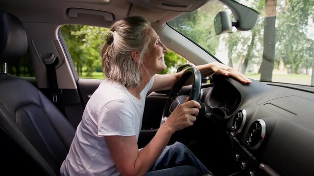 Happy smiling Caucasian old woman touching car inside rejoice buying new own automobile smile excited senior elderly grandmother aged mature glad female buy expensive auto enjoying rent test drive