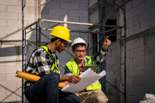 Asian Construction Workers Reviewing Plans on Building Site Construction Project Management for House Development Home Building and Professional Builders