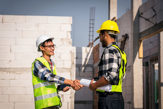 Construction Site Handshake Between Engineers Architects and Builder Team Work with Blueprint Plans Asian Men Industry Partnership Building Concept