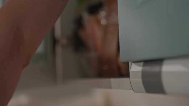 Gentle hand manipulates teal cabinet door delicately. Quiet domestic morning with relaxing lights and subtle sounds. Peaceful start to day featuring gentle movements and comforting ambiance in home