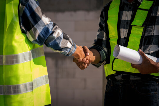Construction Workers Handshake at Building Site Partnership Agreement Business Deal Collaboration Trust Success Safety Vest Architect Inspector Blueprint