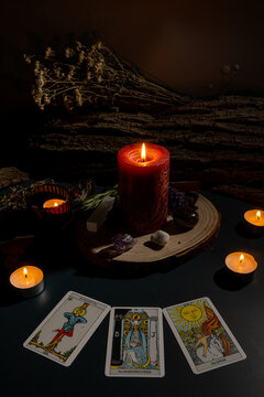dimly lit mystical tarot card reading with candles and dried herbs on wooden table