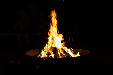 Campfire burns brightly. Orange flames rise. Fire pit glows. Dark night surrounds. © VladyslavShcherbakov