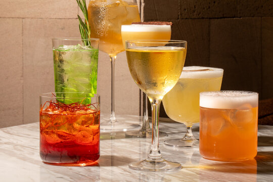 Assorted craft cocktails arranged on a marble bar under warm moody lighting ideal for bar menus, restaurant marketing, cocktail blogs, social media and lifestyle editorial
