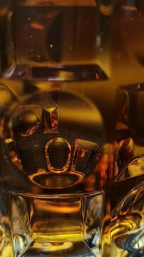Amber whiskey in a glass with reflections, close up drink still life, warm tones, bar beverage.