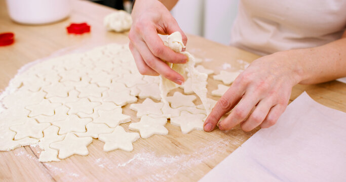 Cooking sweets. Festive pastry recipe. Baker female hand making star shape white cookies on wooden countertop from flour dough sheet.