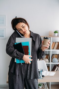 Digital work. Corporate routine. Creative business woman talking on smartphone with laptop coffee using notebook at modern office.