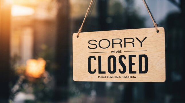 Wooden hanging sign on glass door reading sorry we are closed please come back tomorrow, representing shop closure, business hours, holiday break, temporary shutdown, or store