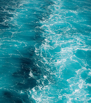Fresh blue ocean waves viewed from above, featuring turquoise water, white foam and a beautiful flowing texture.