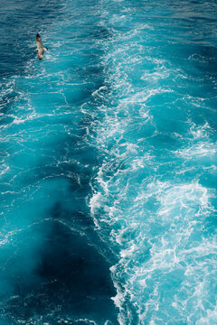 Turquoise ocean water with white foamy waves creating a natural abstract texture and vibrant blue background.