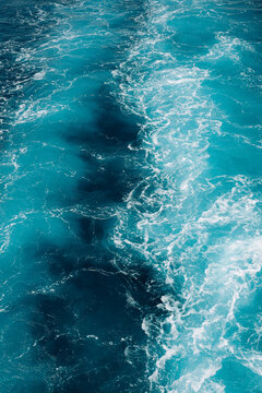 Natural abstract ocean background featuring vibrant turquoise water, energetic waves and delicate white sea foam.