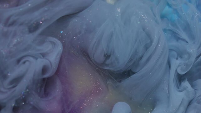 Shimmer paint liquid. Splash pigment. Defocused blue yellow purple color acrylic glitter cloud spreading on abstract creative vibrant art background.