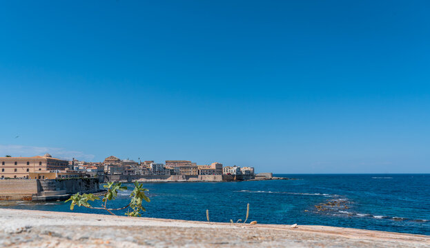 a wide-angle view of the sea and the deep blue sky of Syracuse, visible on the horizon